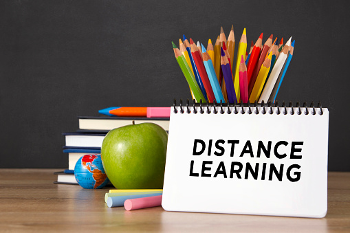 Distance learning concept with school supplies on blackboard background
