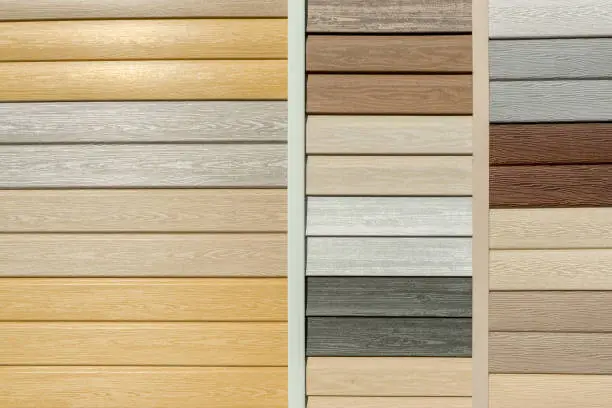 Photo of Vinyl siding with imitation wood texture in bright palette of colors. Plastic wall covering for exterior decoration of house. Abstract background for your design with copy space and place for text