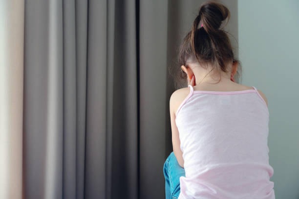 istock A little sad girl sitting on a bed, back view 1223691186