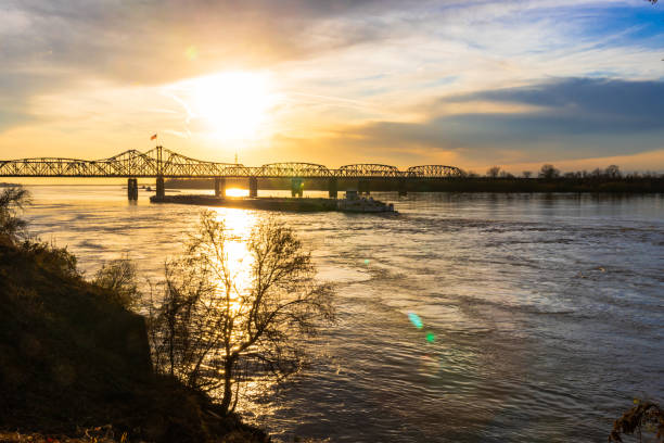 Mississippi River Bridge and towboat with barges at sunset in Vicksburg, MS Sunset landscape of the Mississippi River bridge between Mississippi and Louisiana, in Vicksburg, MS, with towboat pushing barges. vicksburg stock pictures, royalty-free photos & images