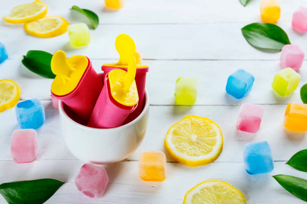 Ice cream popsicles in a bowl with colored ice cubes on a summer picnic stock photo