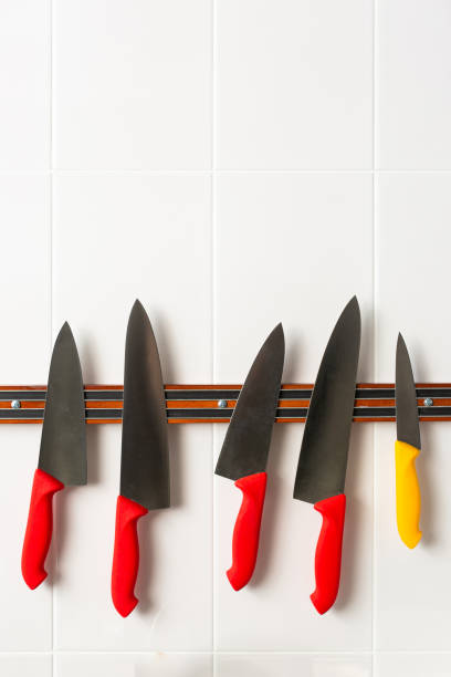 Set of knives on magnetic strip. Collection of knives with colorful handles stock photo