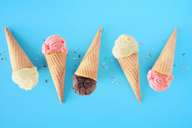 Ice cream cone flat lay over a blue background with vanilla, strawberry and chocolate flavors Ice cream cone flat lay over a blue background. White vanilla, pink strawberry and dark chocolate flavors. vanilla ice cream photos stock pictures, royalty-free photos & images