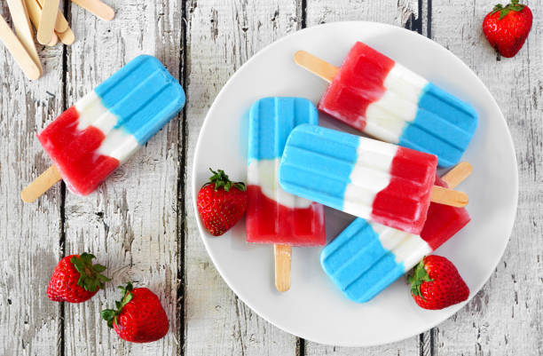 istock Plate of red, white and blue summer fruit popsicles on a white wood background 1223697005