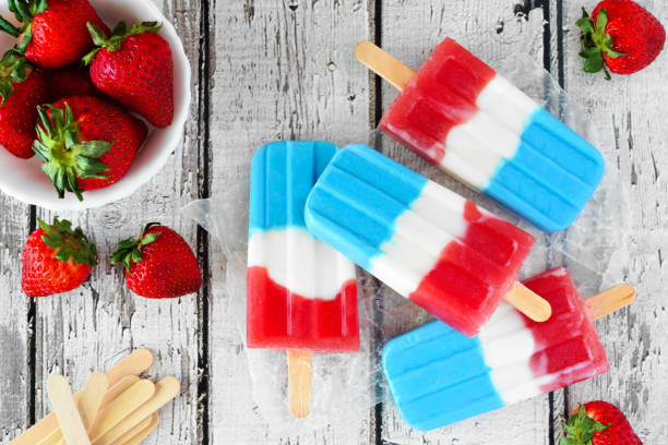 istock Summer red, white and blue fruit popsicles, table scene over rustic white wood 1223697042