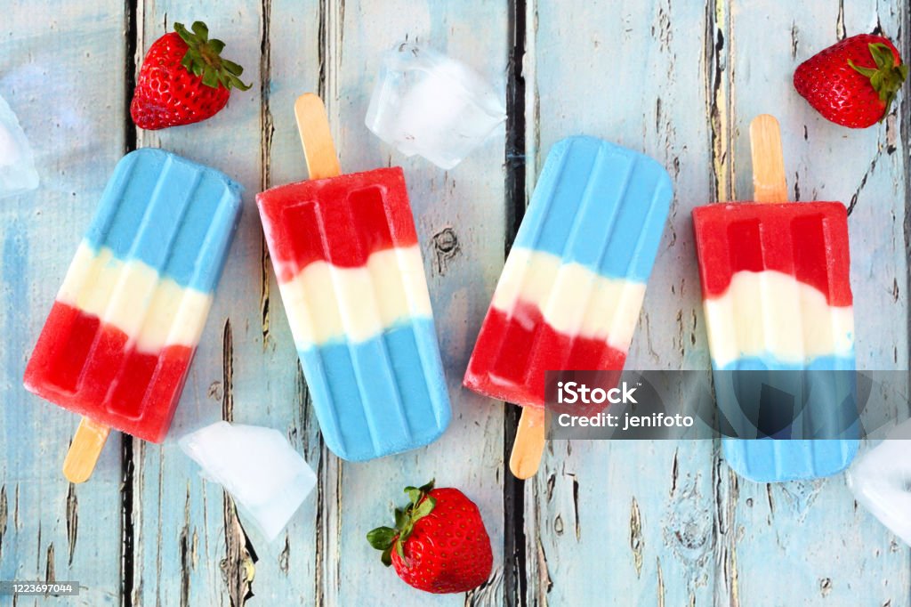 Red, white and blue summer fruit ice pops. on rustic blue wood Red, white and blue summer fruit ice pops. Top view on a rustic blue wood background. July Stock Photo