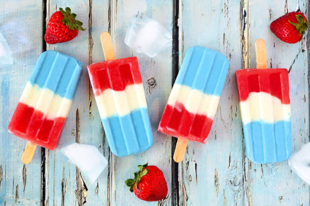 Red, white and blue summer fruit ice pops. on rustic blue wood Red, white and blue summer fruit ice pops. Top view on a rustic blue wood background. july photos stock pictures, royalty-free photos & images