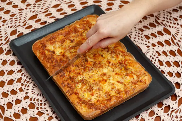 Photo of Top view of woman's hand cutting Brazilian Blender Savoury Pie - Traditional Brazilian food.