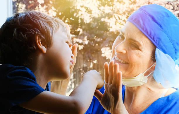 istock Mature Healthcare worker posing seeing her son with a window glass separating them to avoid possible contagion 1223702389