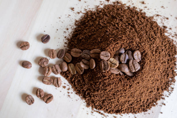 top view of coffee beans and ground coffee on wooden background, roasted coffee volcano like anthill - koffie imagens e fotografias de stock