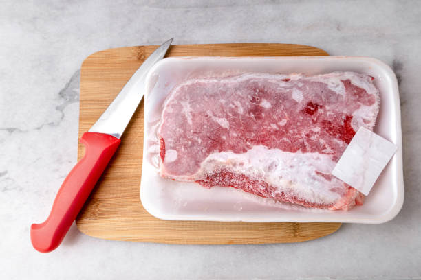 carne congelada y cuchillo en la tabla de cortar - ice pack fotos fotografías e imágenes de stock