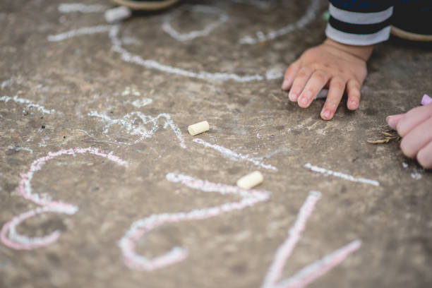 istock Little kid boy drawing numbers with colorful chalks on asphalt 1223708459