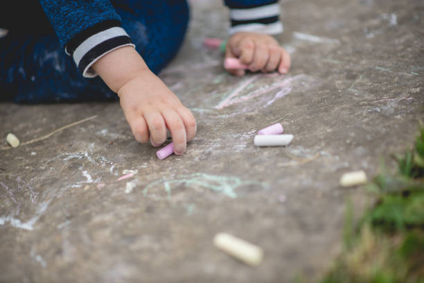 istock Happy little kid boy sitting and drawing with colored chalk on asphalt 1223709109