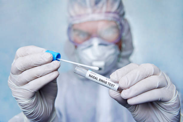 covid-19の診断テスト。病院の実験室で鼻の綿棒の実験室のテスト。綿棒、医学の専門家がサンプルを取る試験管を保持する専門家。科学者の手にチューブを持つ - nasopharynx ストックフォトと画像