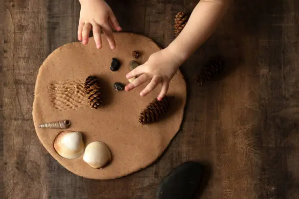 Photo of Modeling with salt dough on the kitchen table. Natural materials for the game, the natural composition of the product. Creative development of children in the period of self-isolation