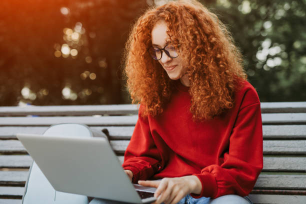 istock Young woman sitting on bench and using laptop 1223714384