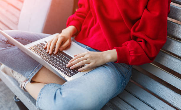 Young woman sitting on bench and working on laptop