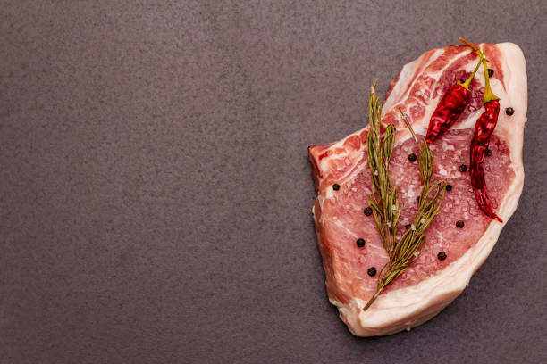 istock Raw pork steak on trendy black stone concrete background 1223715888