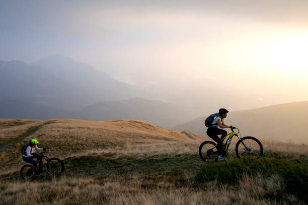 istock Two women ride up grassy hillside on electric mountain bikes 1223721732