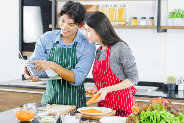 istock Asian couple in apron uses notebook in kitchen. 1223729362