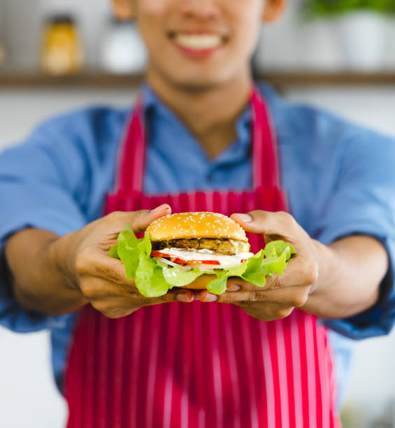 istock Asian man holds hamburger in his hands. 1223729394