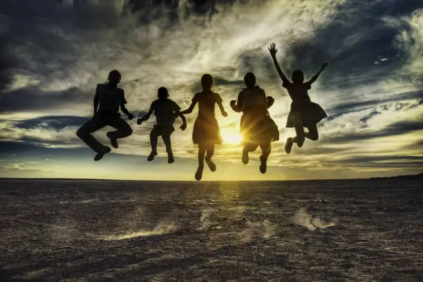 Group of african kids jumping in the sunset, Botswana