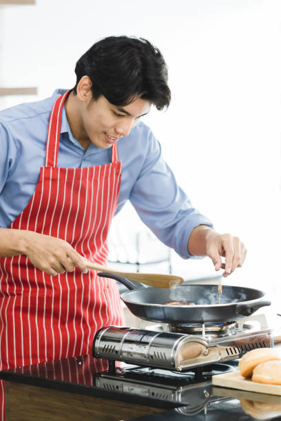 istock Asian man fried hamburger in pan on stove. 1223740925