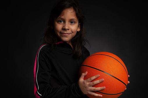 young basketball player holding ball and looking at camera