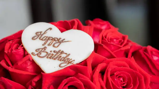 The heart shape is made of sugar and the HappyBirtday text on the rose is blurred.