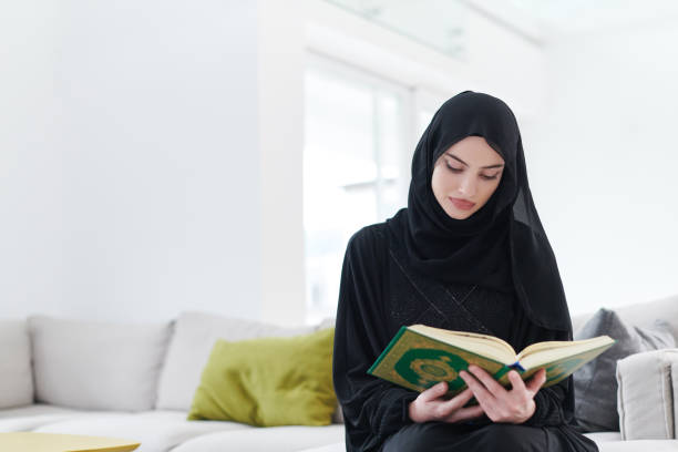 young muslim woman reading quran at home - prayer call imagens e fotografias de stock