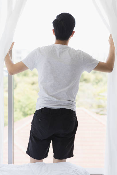 istock Man open the curtain and look outside the window. 1223749650