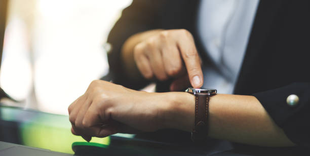 una donna d'affari che indica un orologio da polso sul suo tempo di lavoro durante l'attesa di qualcuno - checking the time women impatient wristwatch foto e immagini stock