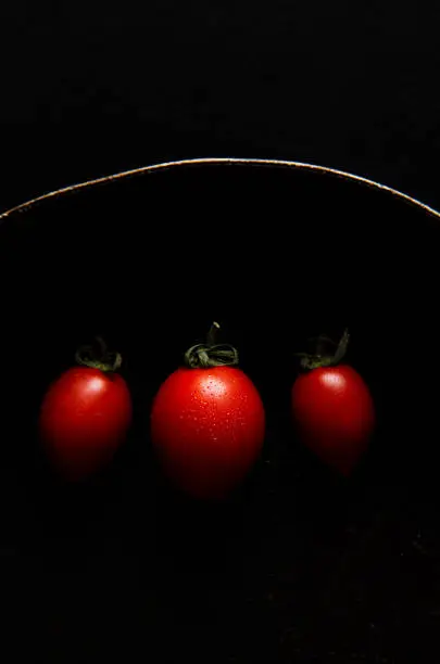 Red fresh healthy tomatoes isolated on a black cuisine pan