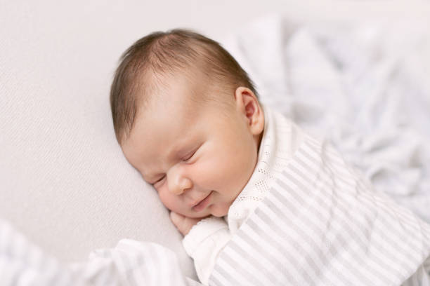 istock newborn baby sleeps under the covers and smiles 1223753079