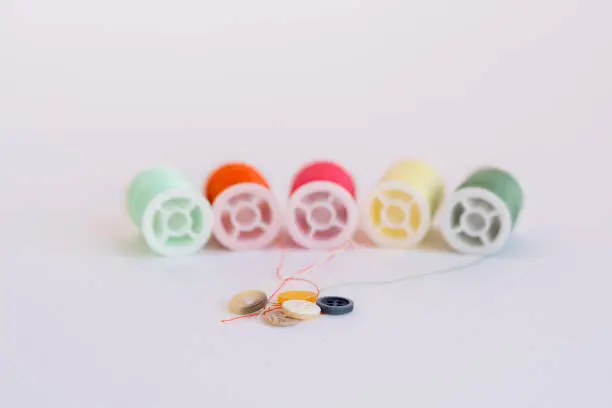 Colorful sewing thread reels and fashion buttons isolated on a white background