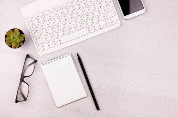 istock Business concept. Work from home. Office flatlay with white keyboard, reading glasses, pet and notebook. Top view 1223754841