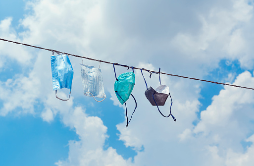 Fabric face-masks are hanging in rope, for drying in sunlight. Shot on a sunny day in Kolkata, India during coronavirus lockdown.