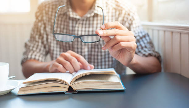 istock The young man with vision problems is picking up his glasses and reading a book. 1223767201