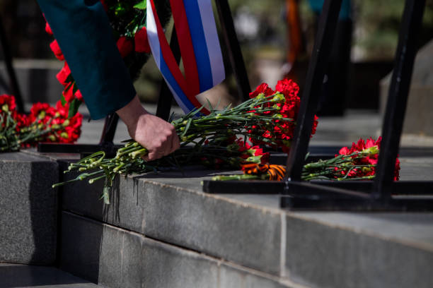 istock A hand puts red carnations on a granite gravestone. Memory of the dead 1223768143