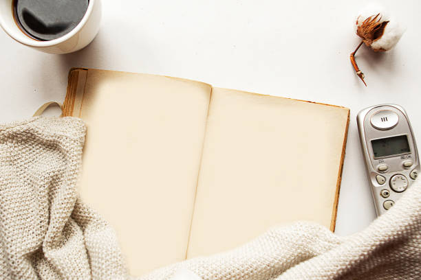 istock Flat lay photo with old open book, coffee cup and phone on white background. Pastime concept. Quarantine concept 1223771640