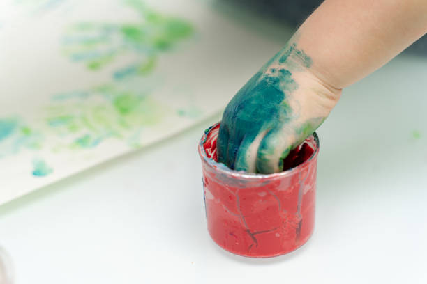 istock Little girl paints with fingers 1223772553