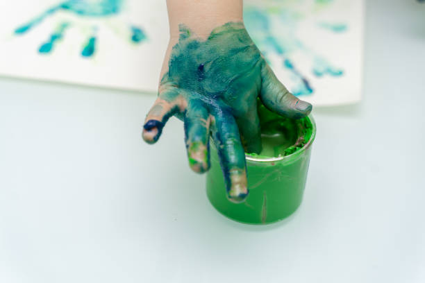 istock Little girl paints with fingers 1223772574