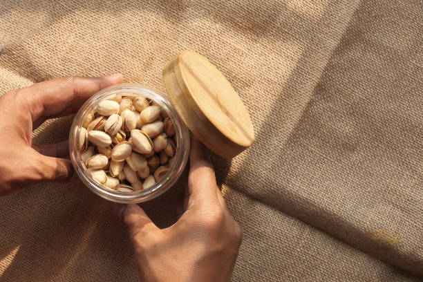 istock Man hand holding a jar of salted pistachios 1223773190