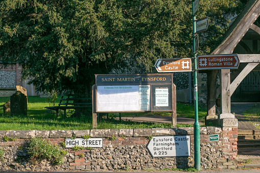 Eynsford High Street in Kent, England, with signs towards Lullingstone Roman Villa, Eynsford Castle, Farningham and Dartford. In the background is the signboard for St Martin's Church.
