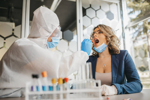 männlicher arzt in schutzanzügen, der tupfertest von junger patientin nimmt - dna epidemiology patient science stock-fotos und bilder