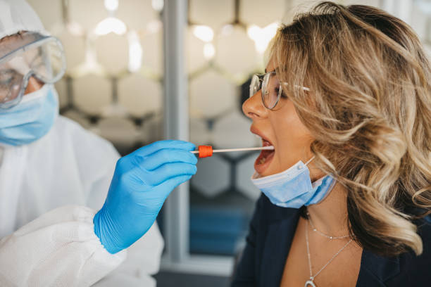 männlicher arzt im schutzanzug bei tupfertest von junger patientin - dna epidemiology patient science stock-fotos und bilder