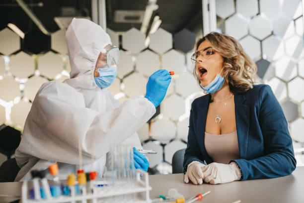 männlicher arzt im schutzanzug bei tupfertest von junger patientin - dna epidemiology patient science stock-fotos und bilder