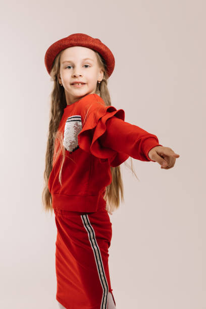 istock Little girl in a red suit and hat posing on a light background 1223778508