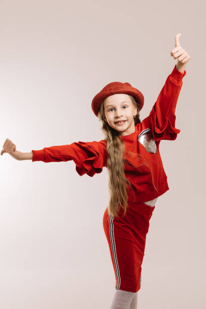 istock Little girl in a red suit and hat posing on a light background 1223779726