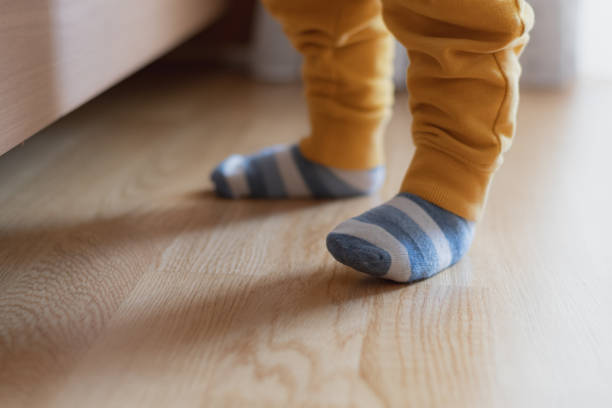 istock Baby feet with striped socks, standing and trying his first steps, selective focus 1223781084